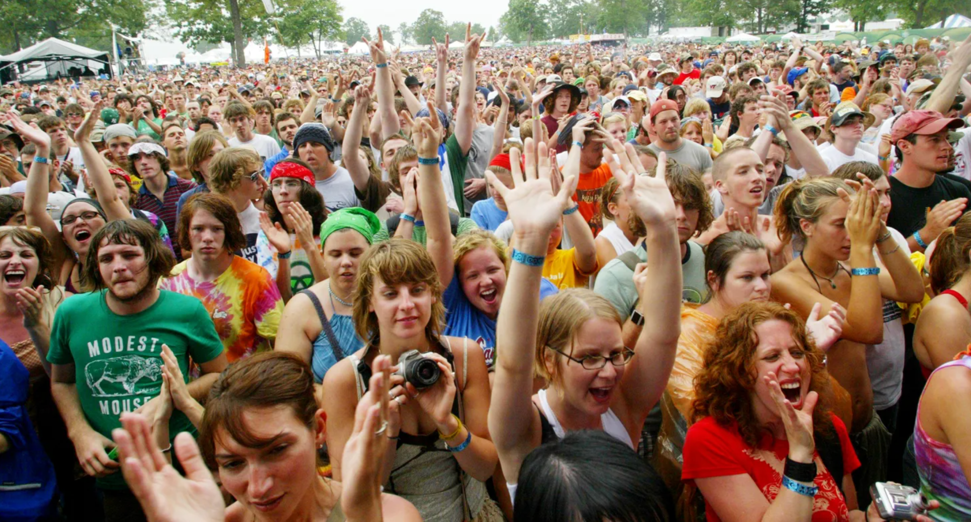 Large crowd at an outdoor event, cheering with raised arms. Green and red shirts visible.