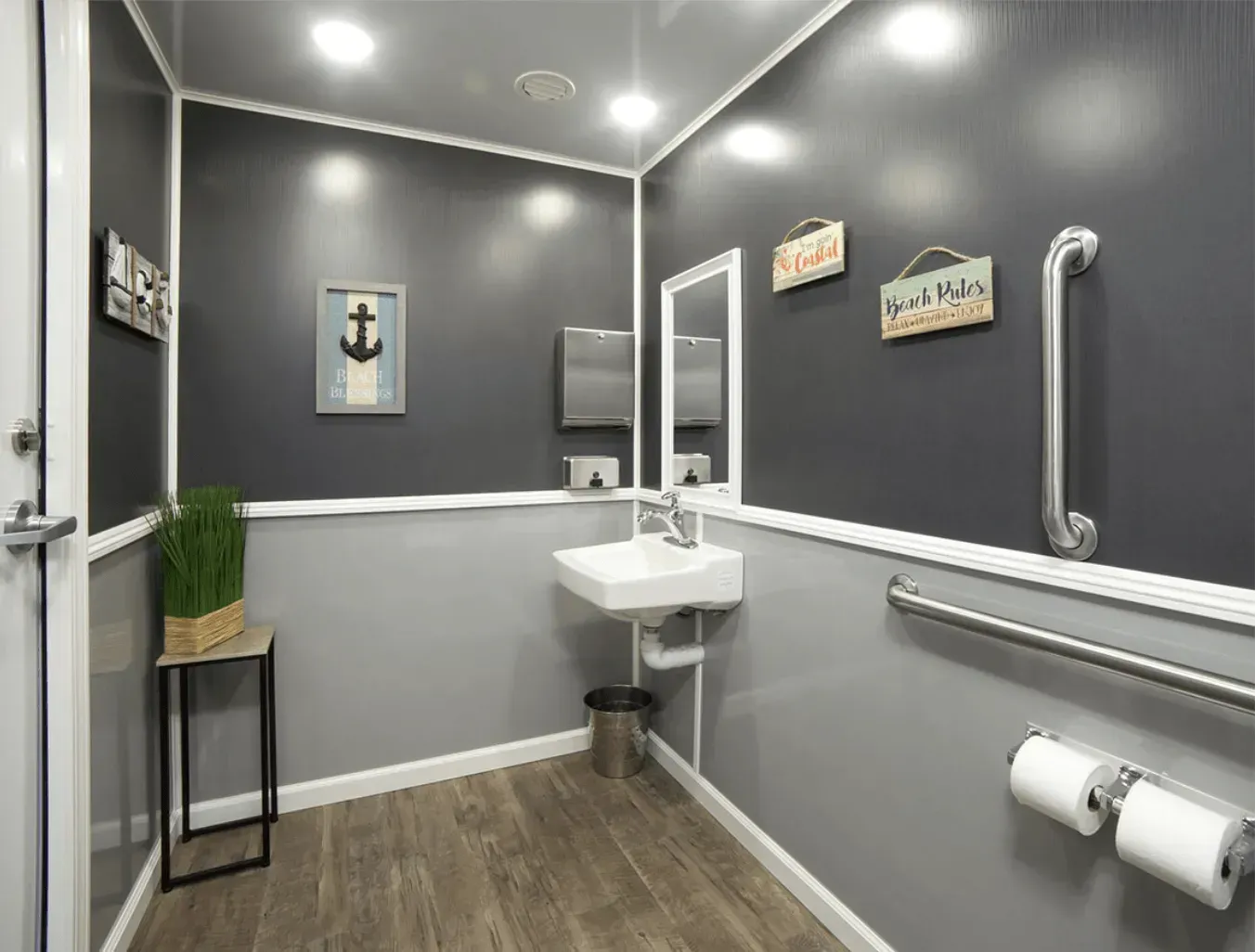 Accessible restroom with gray walls, white trim, and a small sink. Includes a grab bar and paper towel dispenser.