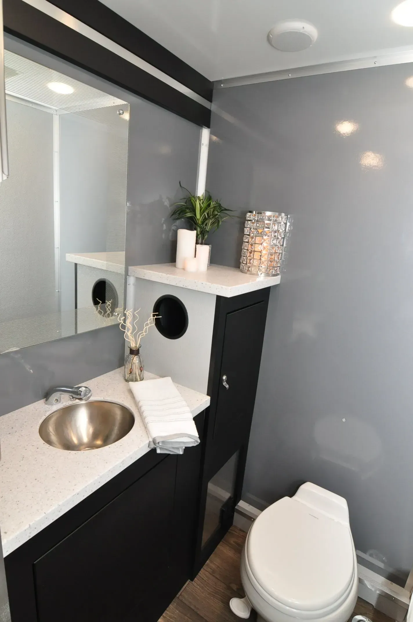 Bathroom interior with a sink, toilet, and decorative shelf. Gray walls, white countertop, and black cabinet.