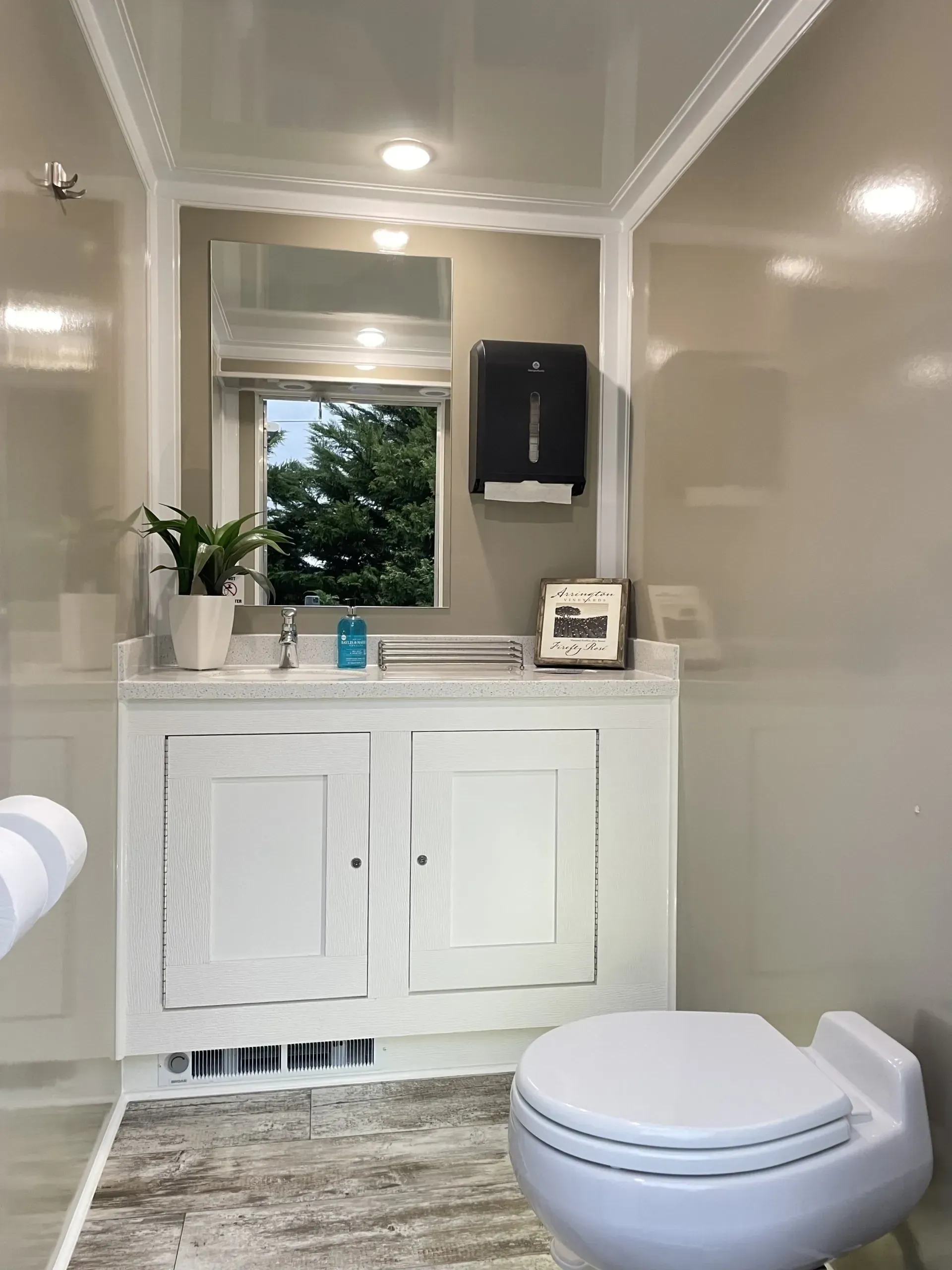 Interior of a portable restroom with a sink, mirror, and toilet.