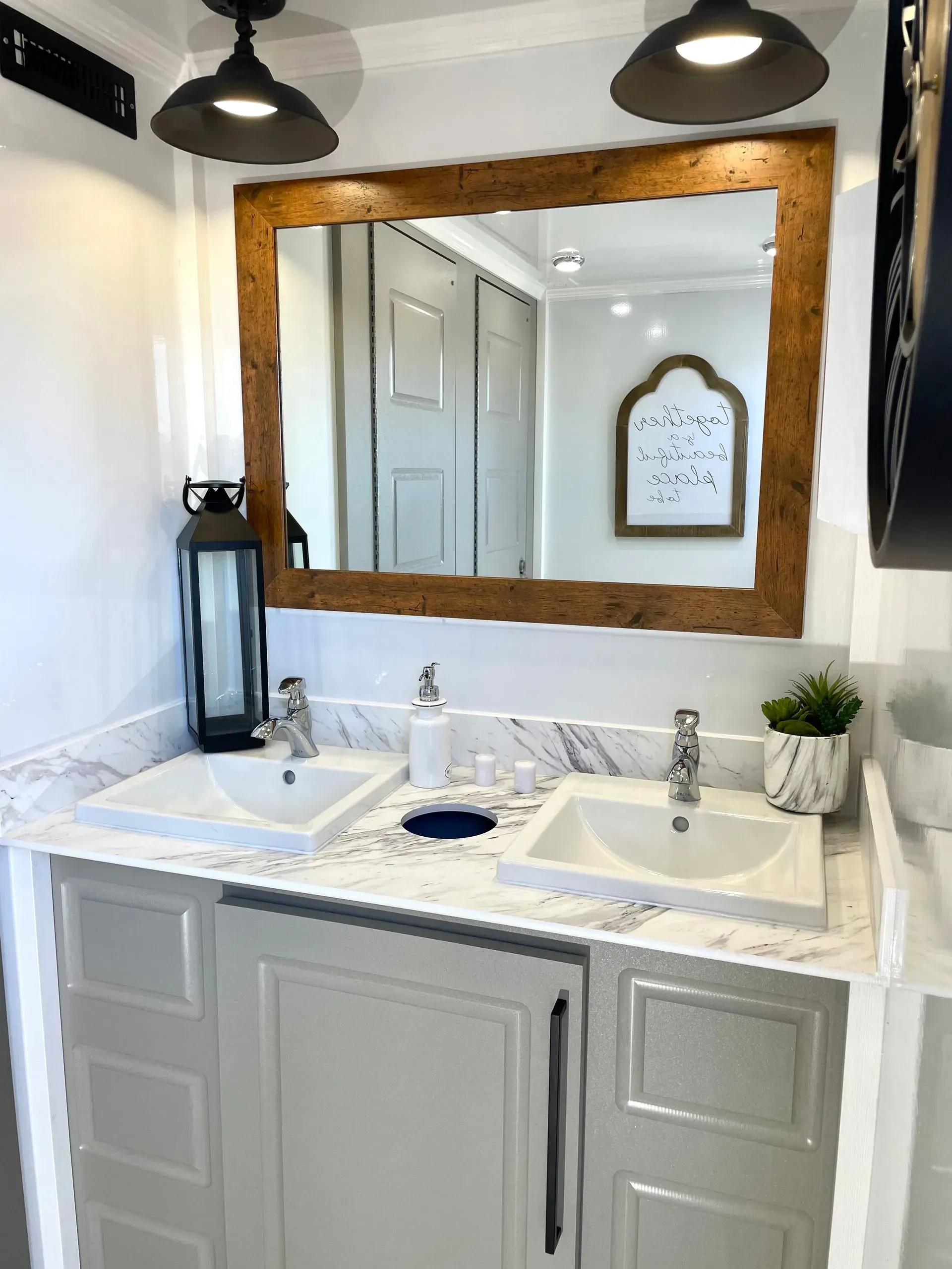 Bathroom with double sinks, large mirror, and decorative lighting.