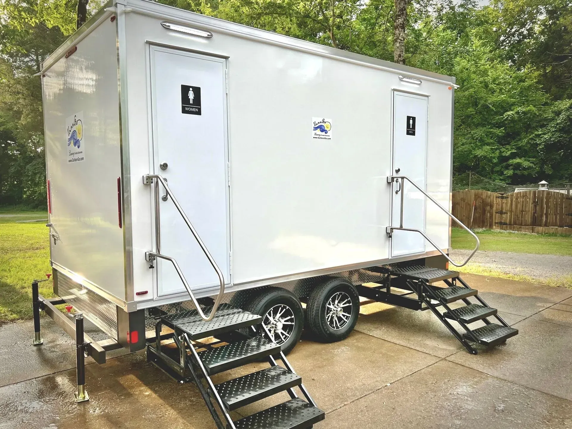 A white portable restroom trailer with two separate entrances and steps.