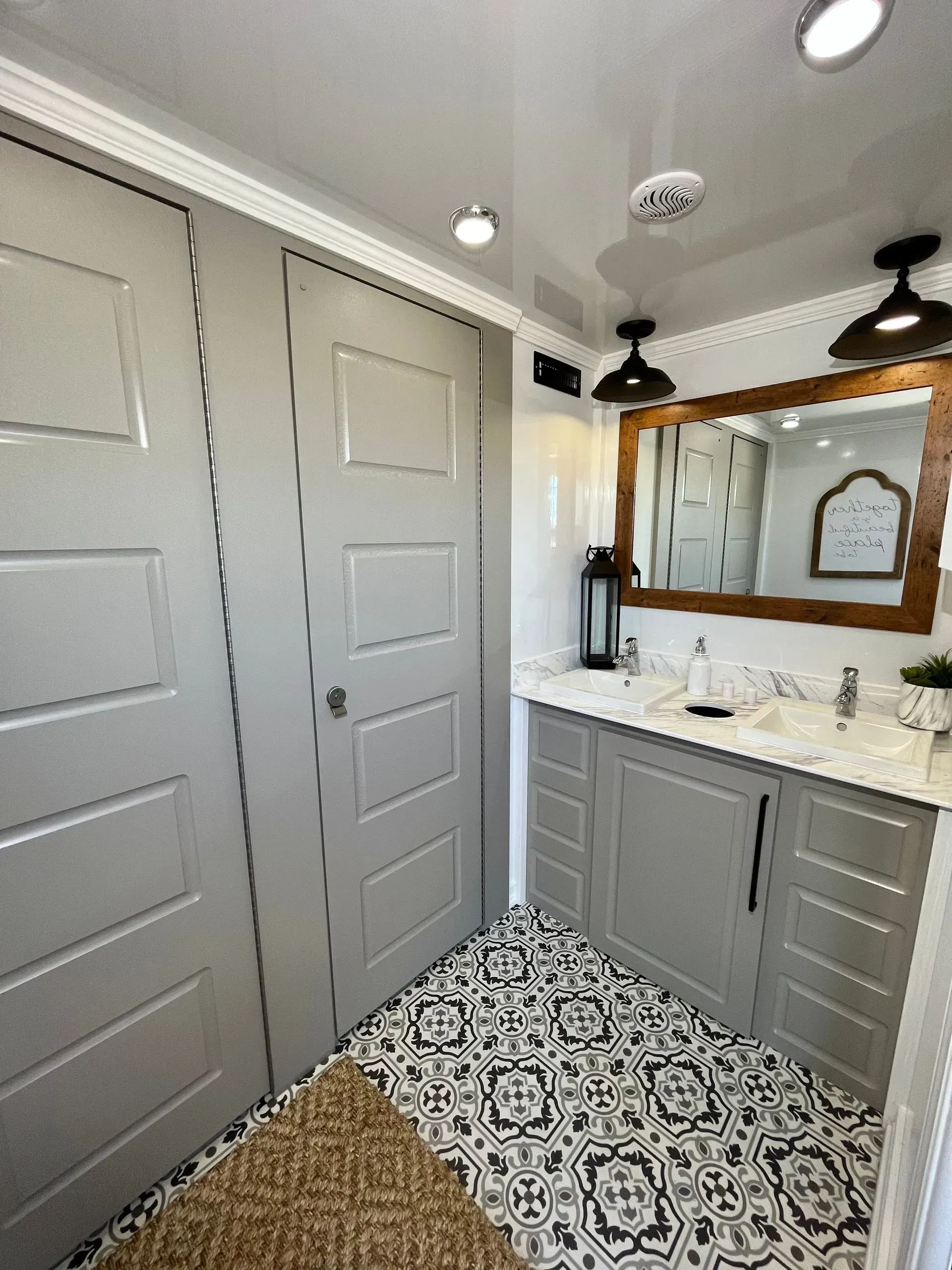 Bathroom with gray cabinets, patterned floor, and large mirror framed in wood.