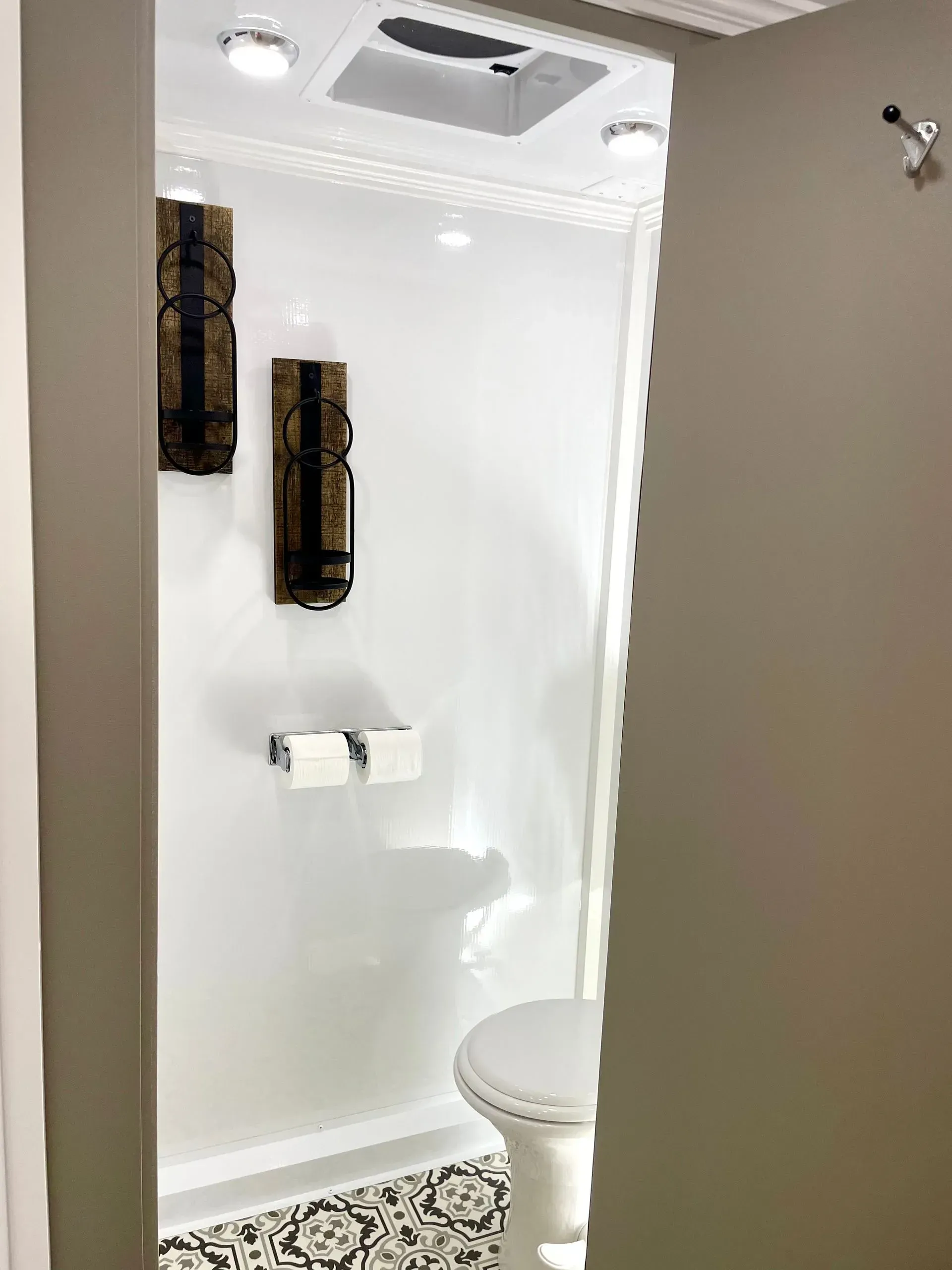 Small, white bathroom with decorative wall art, toilet, and patterned floor.