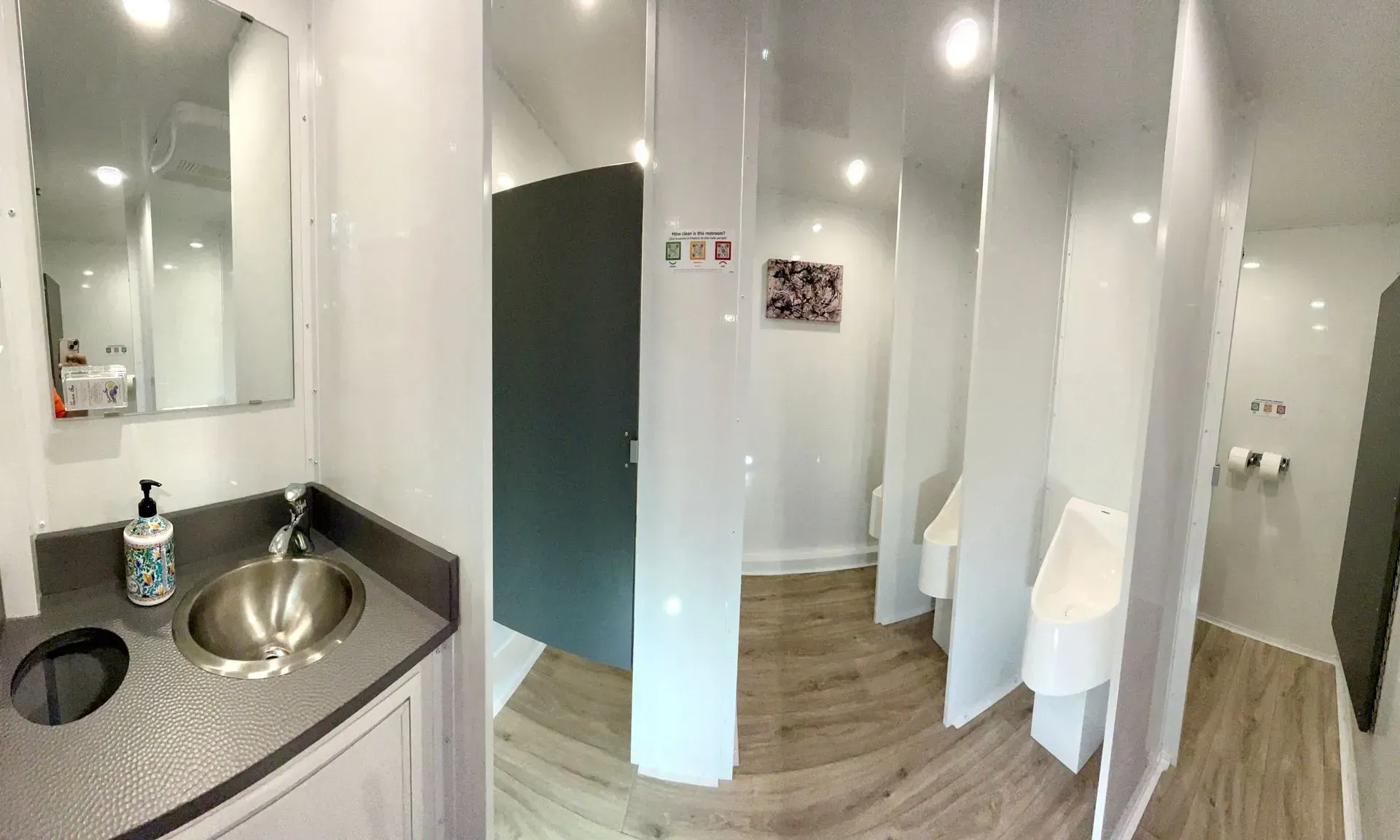 Interior of a portable restroom with sinks, urinals, and individual stalls.