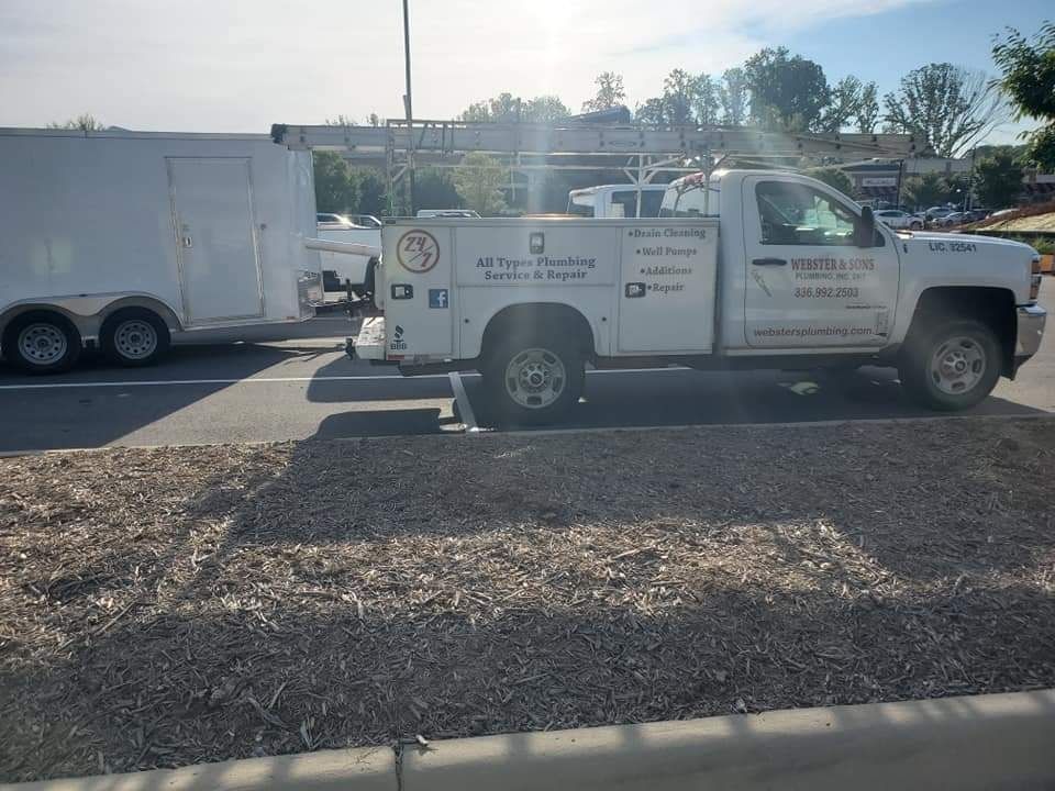 White truck with trailer parked in a lot, possibly a plumbing service vehicle.