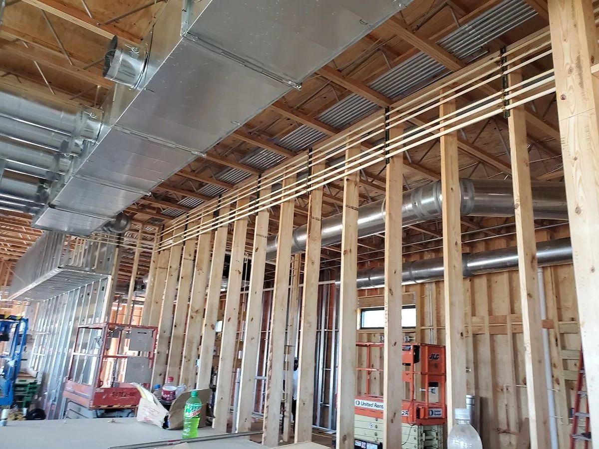 Interior of a building under construction, showing wooden framing, ductwork, and pipes.