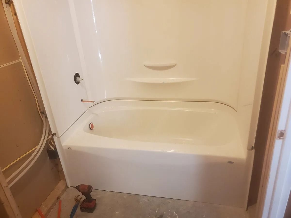 White, unfinished bathroom with installed bathtub and shower combo.