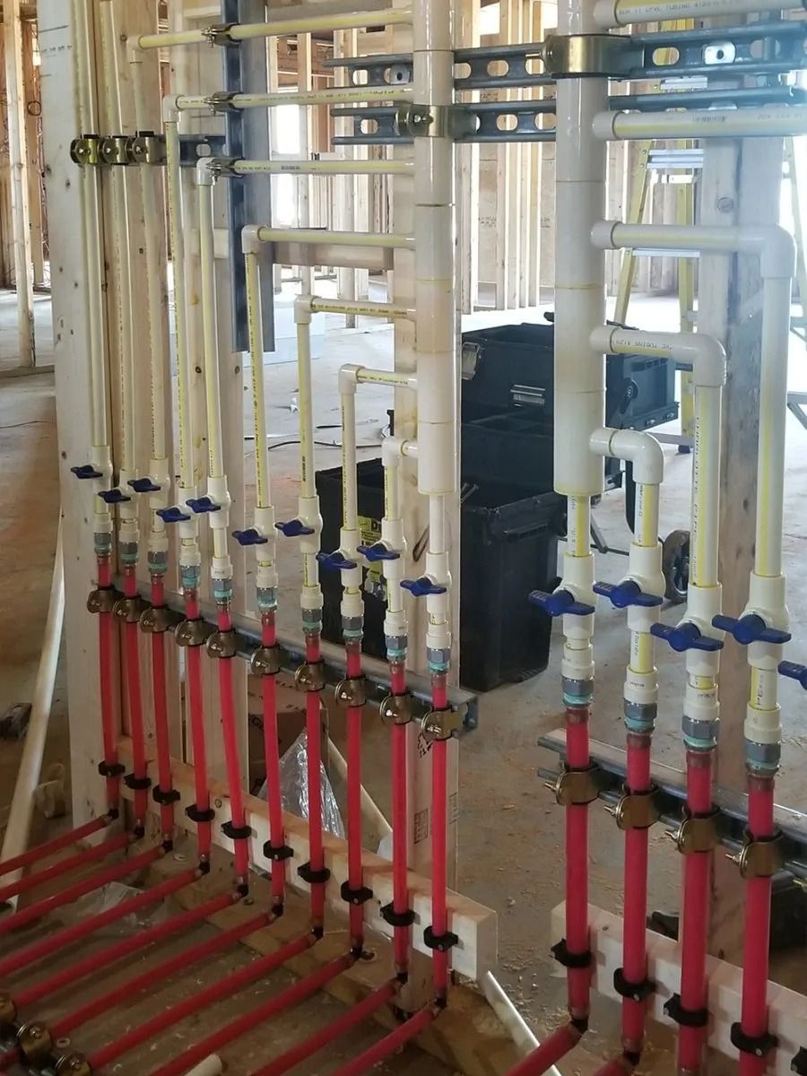 Piping system with red and cream-colored pipes and valves, installed in a wooden-framed building.