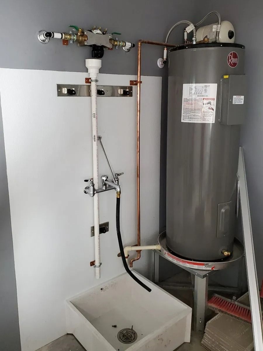 Water heater and utility sink in a utility room. Copper and PVC pipes are visible.