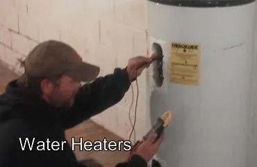 Man tests a water heater with a multimeter in a basement.
