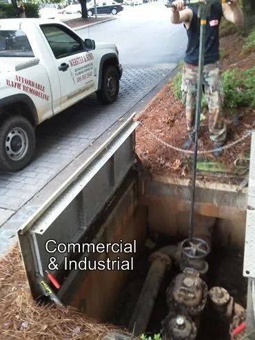 Man operating a valve in a concrete vault next to a truck. 