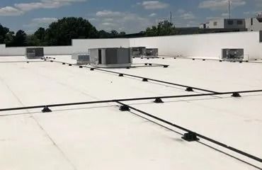 White rooftop with HVAC units and black conduit lines.