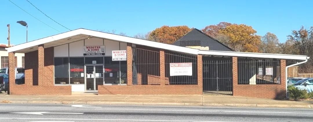 A one-story brick building with a white roof. The building has large glass windows and doors.