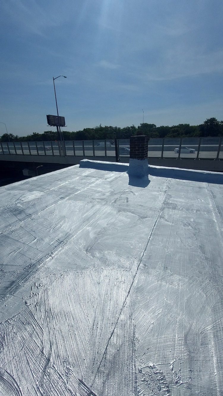 Bright rooftop walkway with white coating, railings, and a blue sky overhead