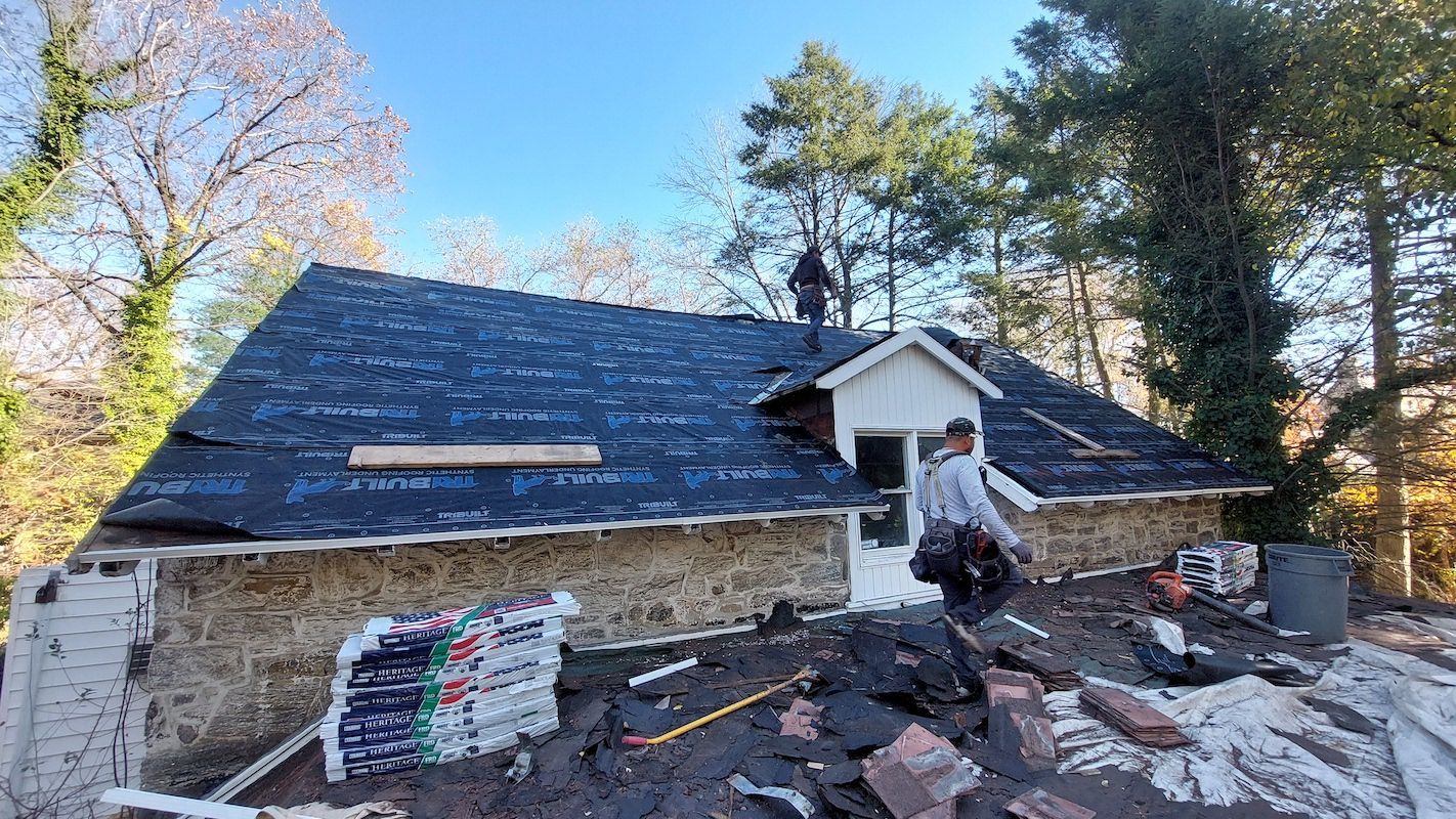 Partially repaired house roof with workers and construction debris in the yard
