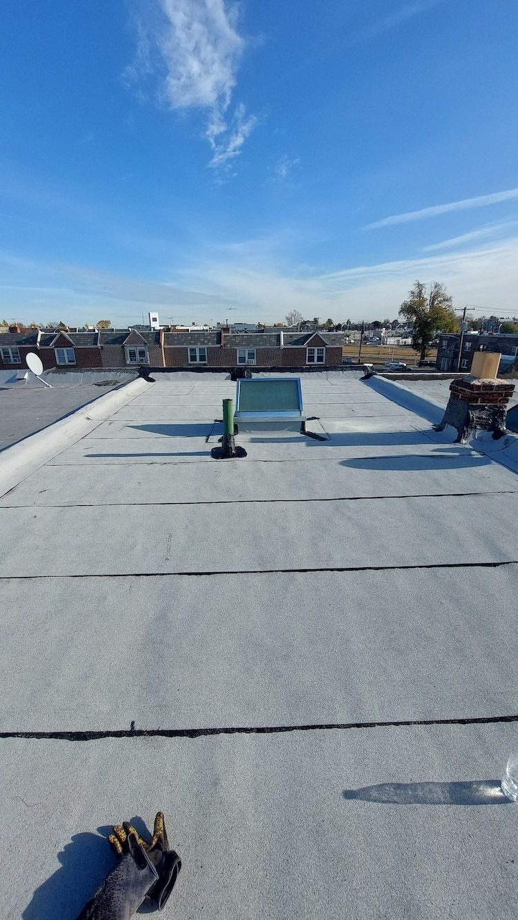 Rooftop with gravel surface, vents and pipes under a clear blue sky.