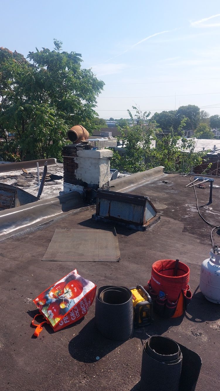 Rooftop with garden supplies, buckets, bags, and a small chimney under a bright sky.