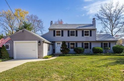 Suburban house with attached garage, front lawn, and an American flag on a sunny day