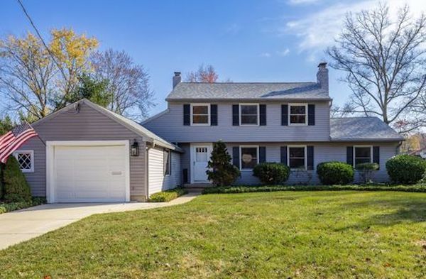 Suburban house with attached garage, front lawn, and an American flag on a sunny day
