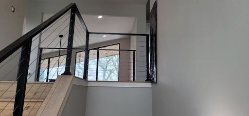 a staircase with a metal railing in a house with a lot of windows .