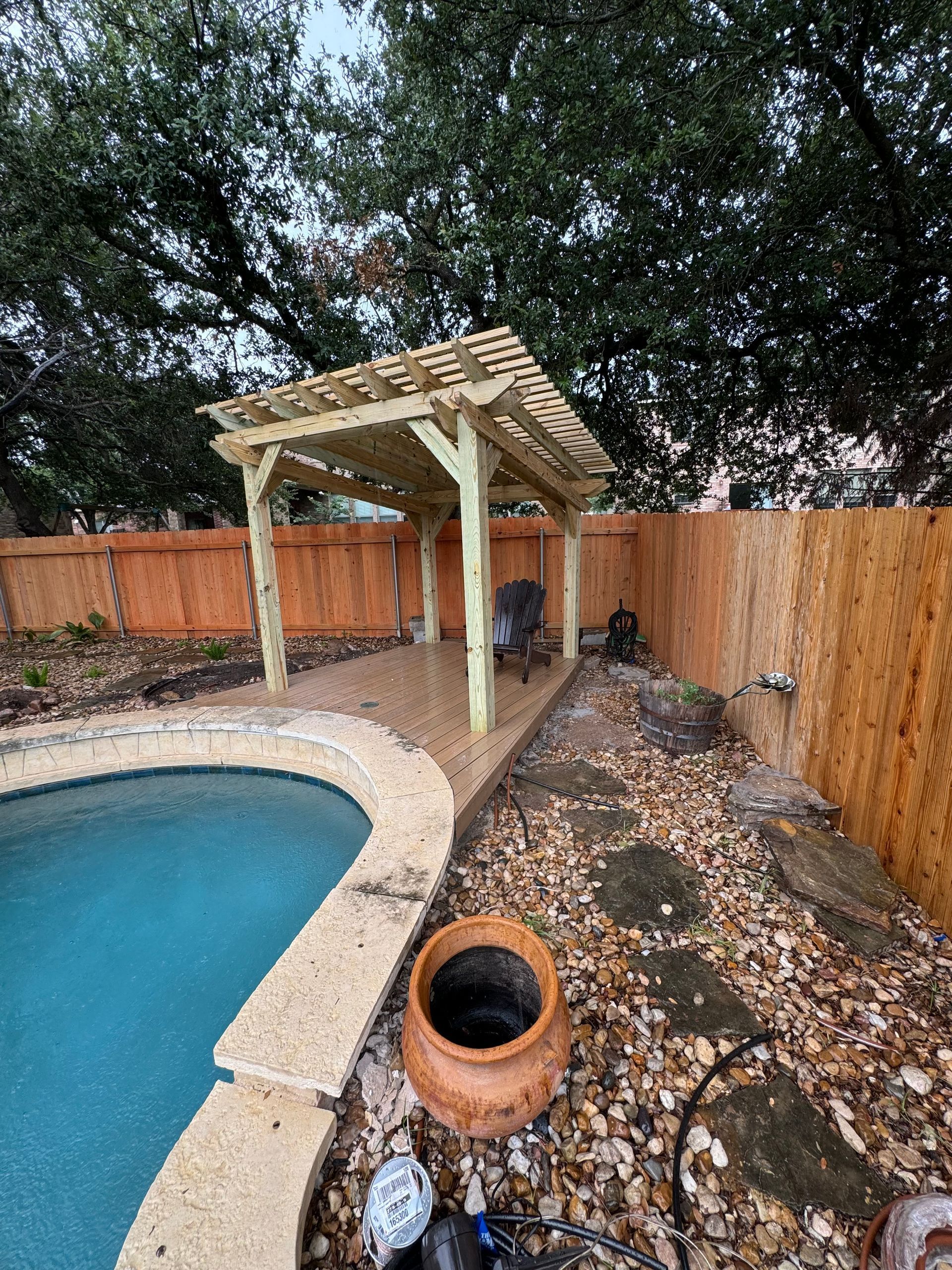 A wooden pergola is sitting next to a swimming pool.
