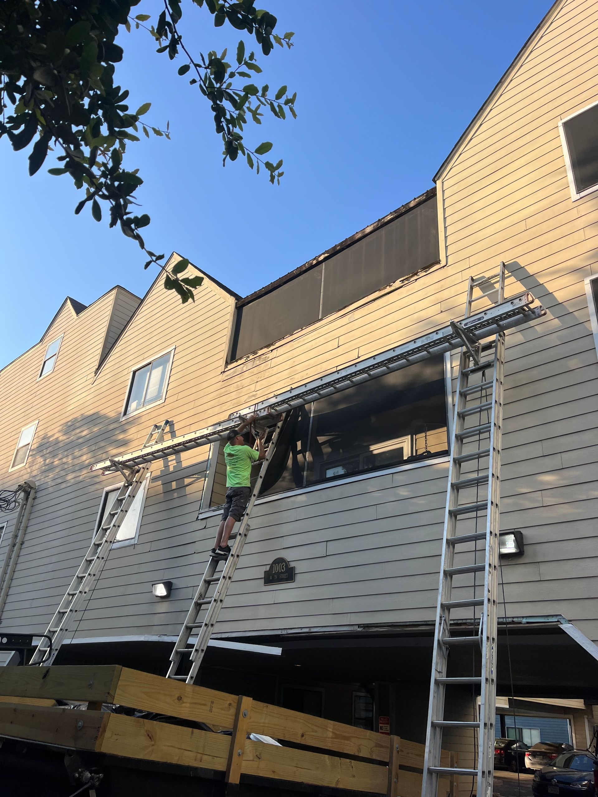 A man on a ladder is working on the side of a building.