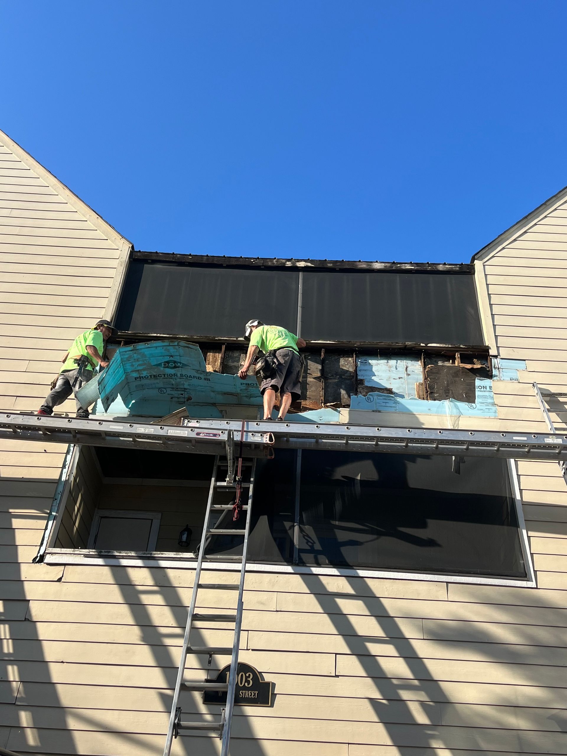 Two men are working on the roof of a house.