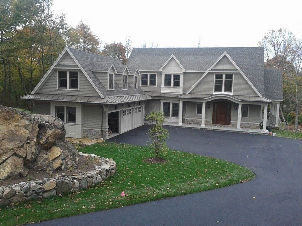 Large gray house with attached garage and dark asphalt driveway.