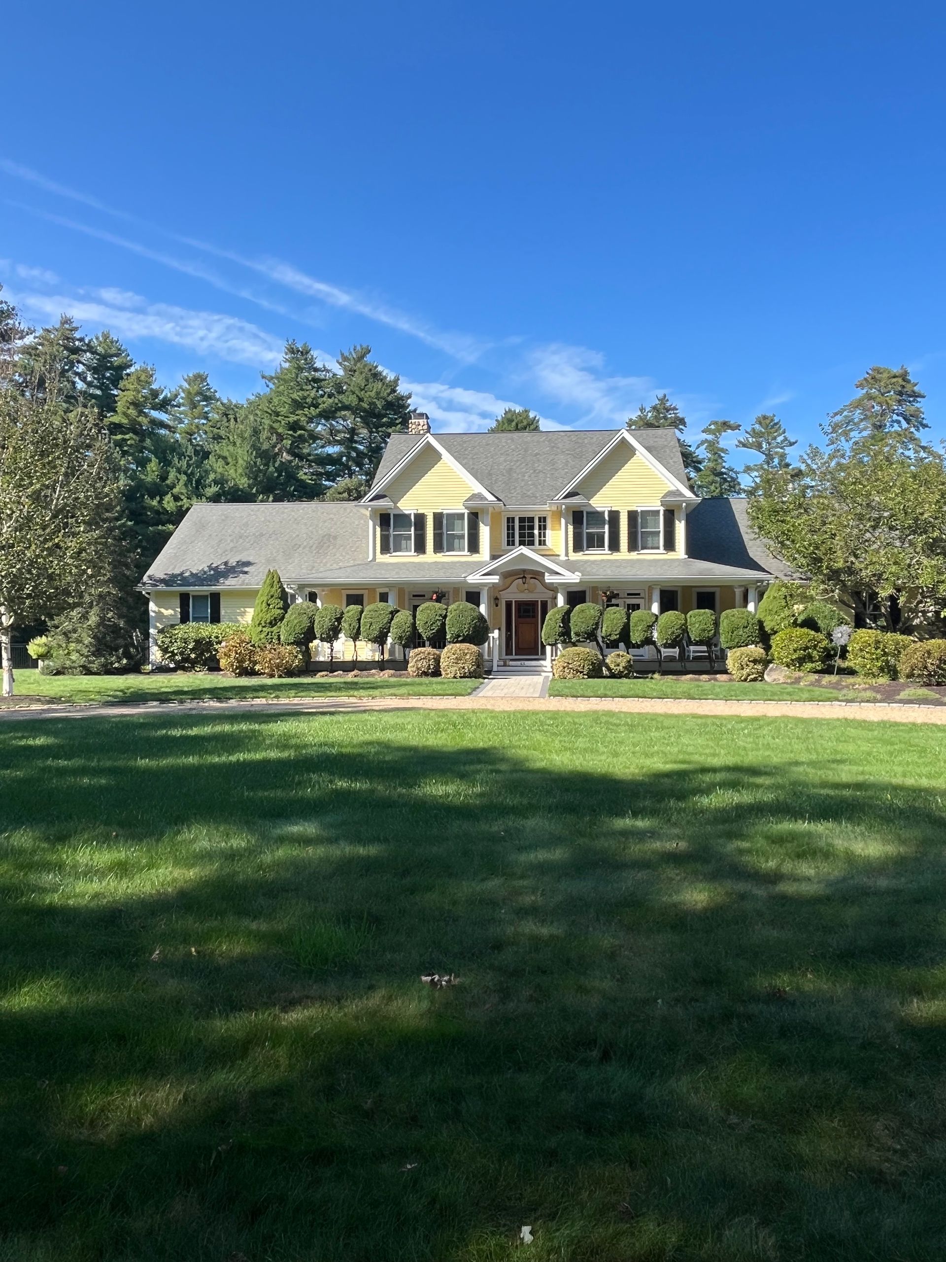 Yellow two-story house with green lawn and blue sky.