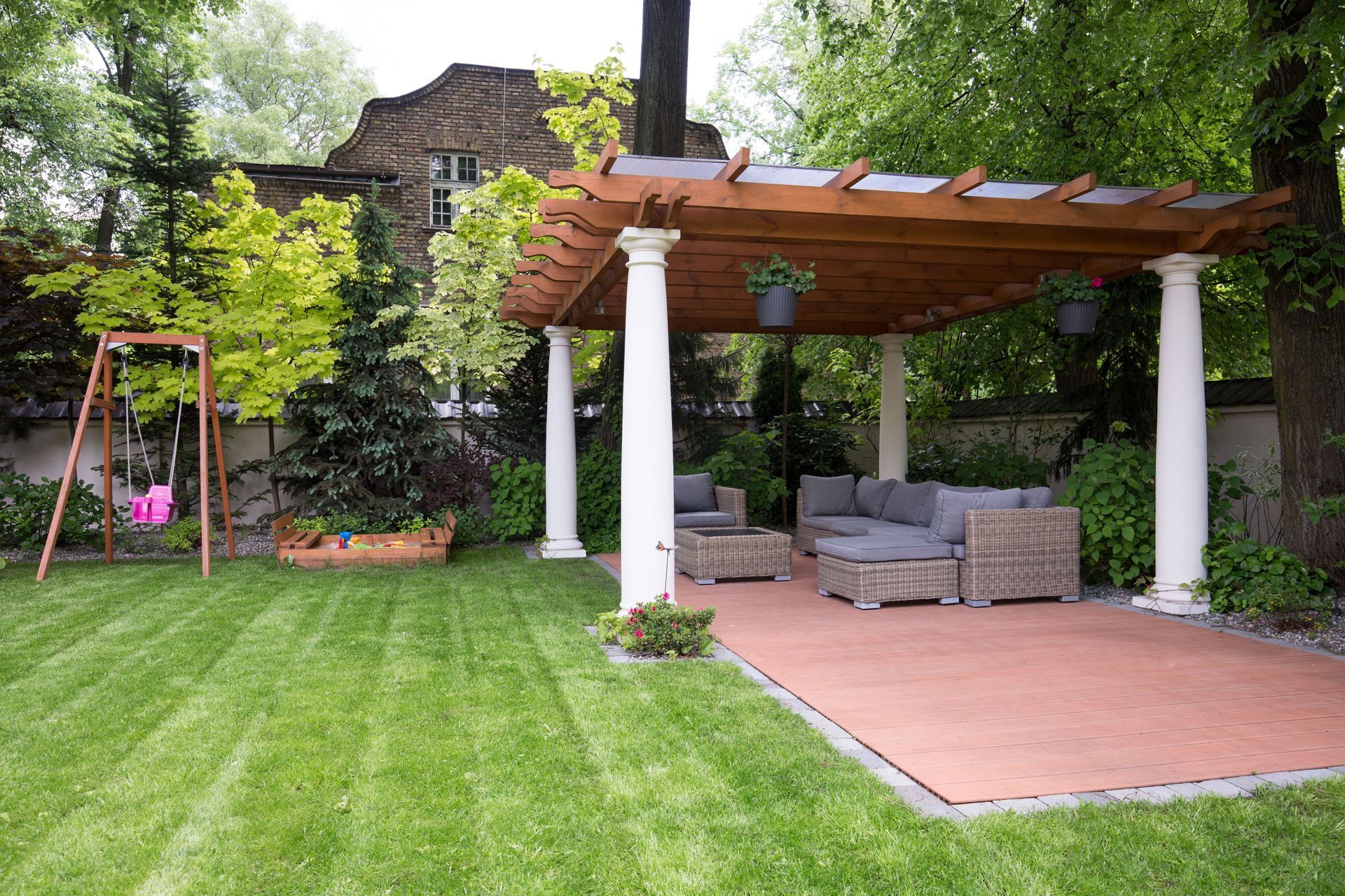 Backyard patio with pergola, outdoor seating, swing set, and lush green lawn