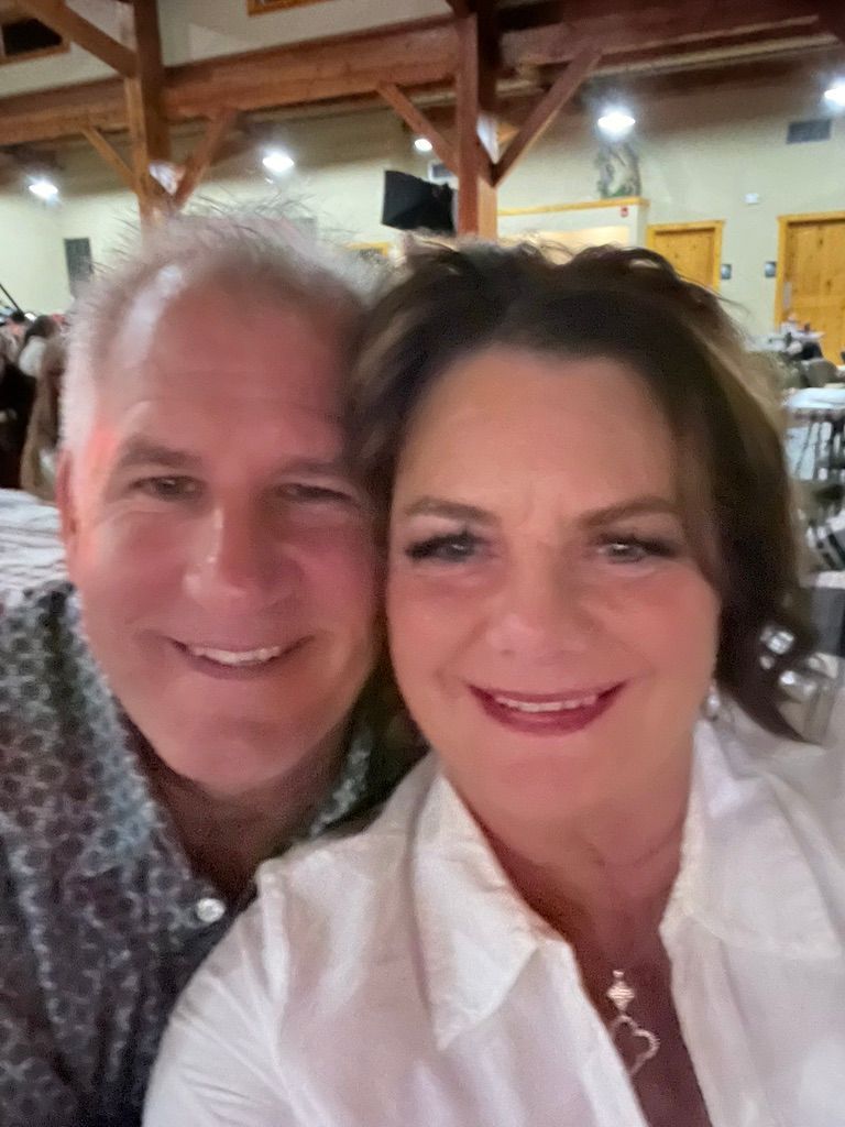 Two people smiling indoors at a warmly lit restaurant or event venue