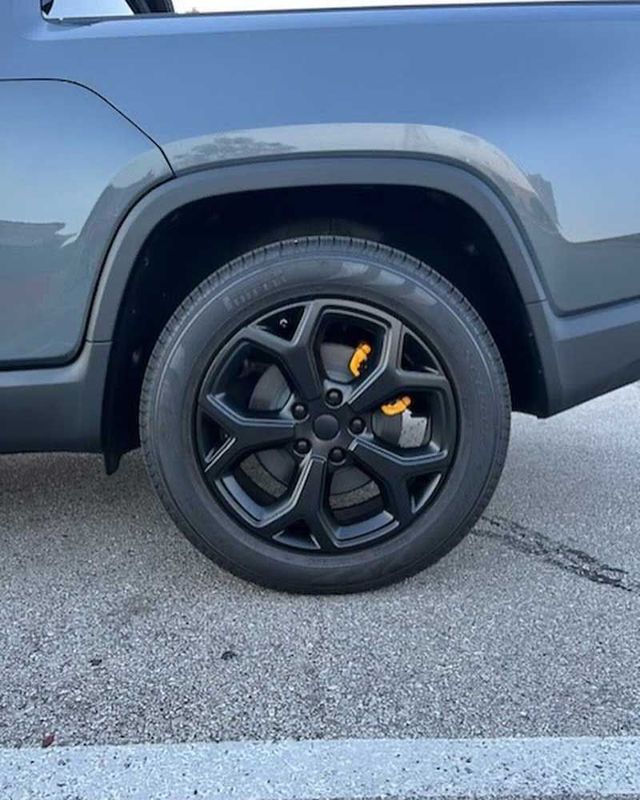 Black car wheel with black rim and yellow brake caliper.