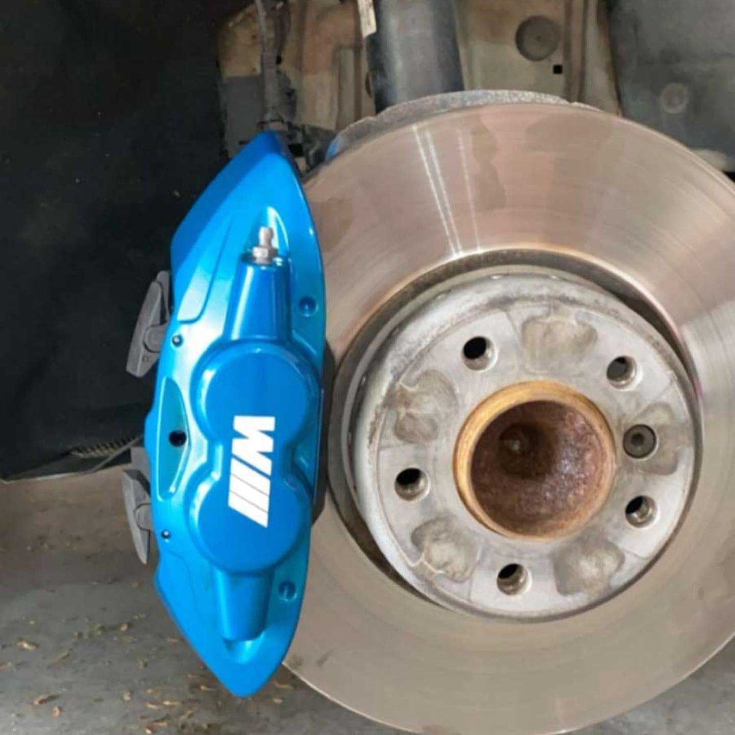 Blue BMW M brake caliper on a silver brake rotor.