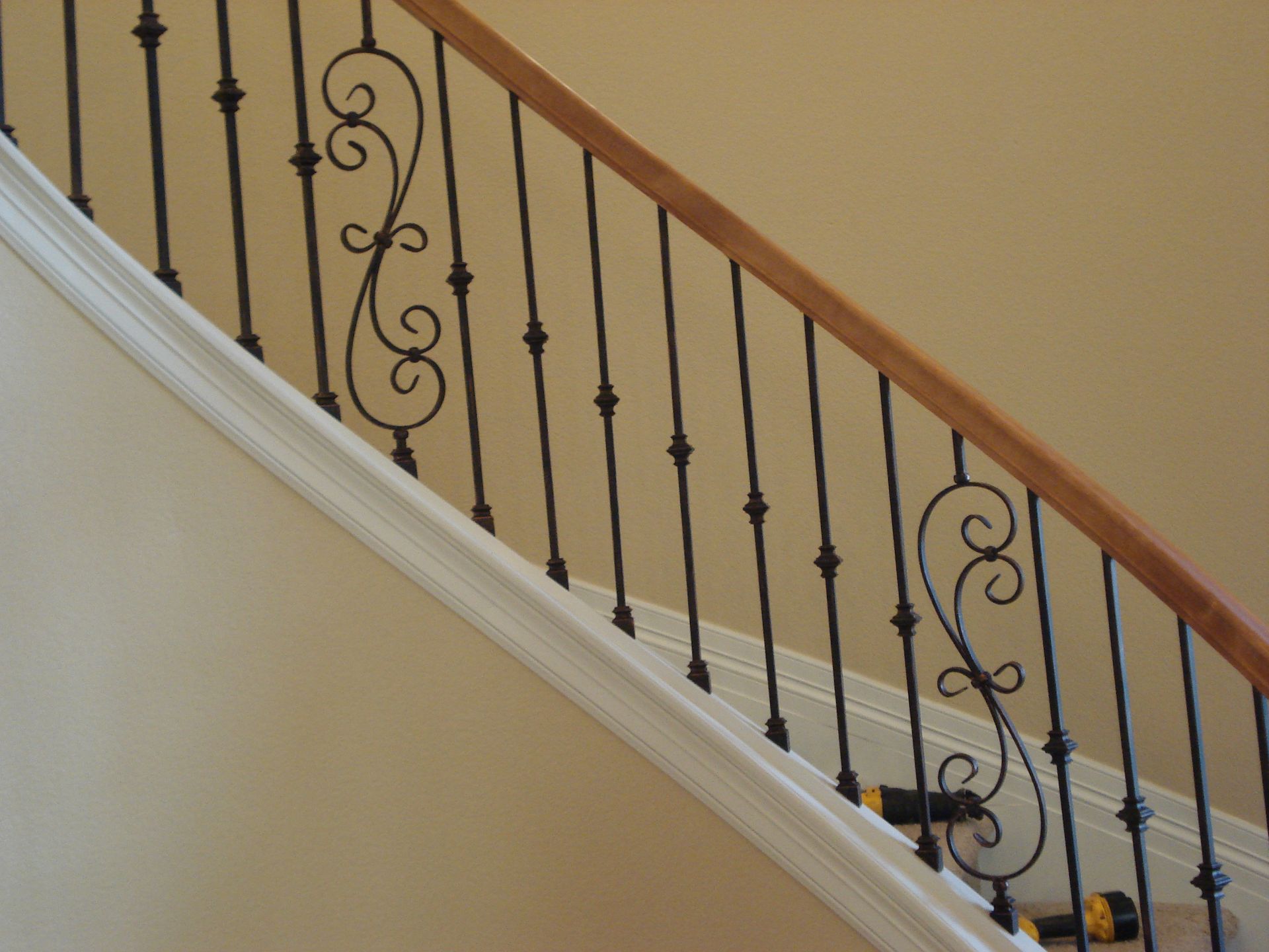 A staircase with a wrought iron railing and a wooden handrail