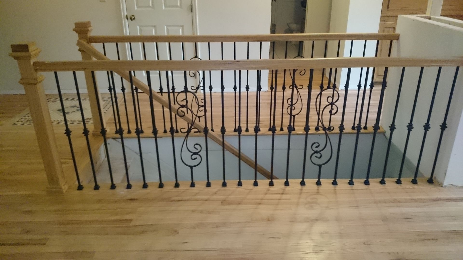A wooden staircase with a wrought iron railing in a house.