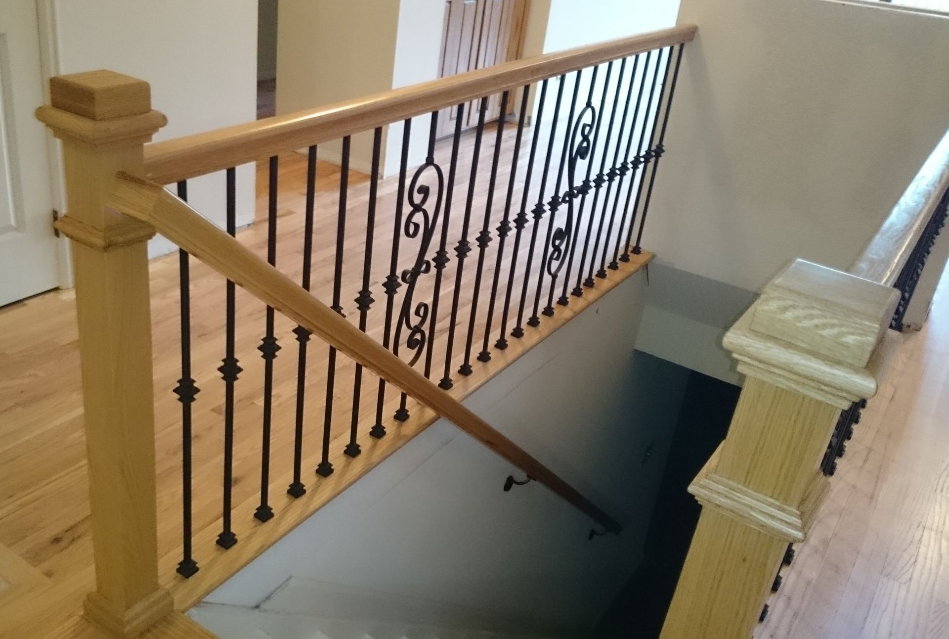 A staircase with a wooden railing and wrought iron balusters