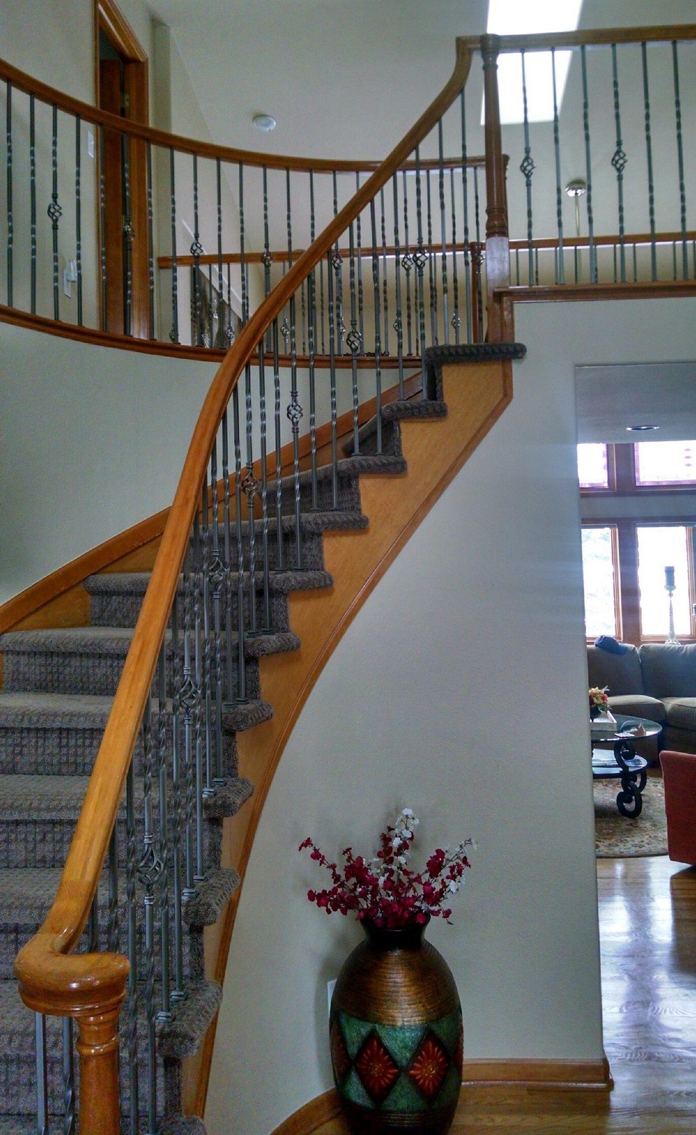 A vase of flowers sits on a table next to a staircase