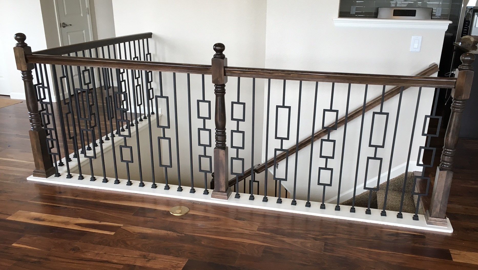A wooden staircase with a wrought iron railing in a house.