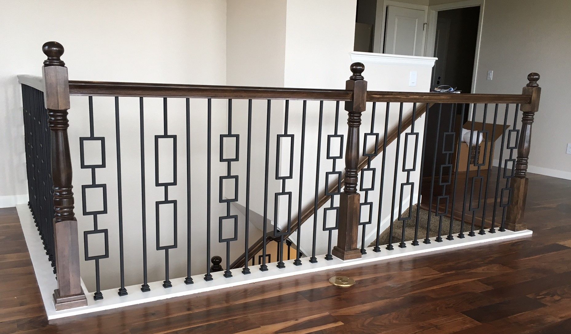 A wooden staircase with a wrought iron railing in a house.