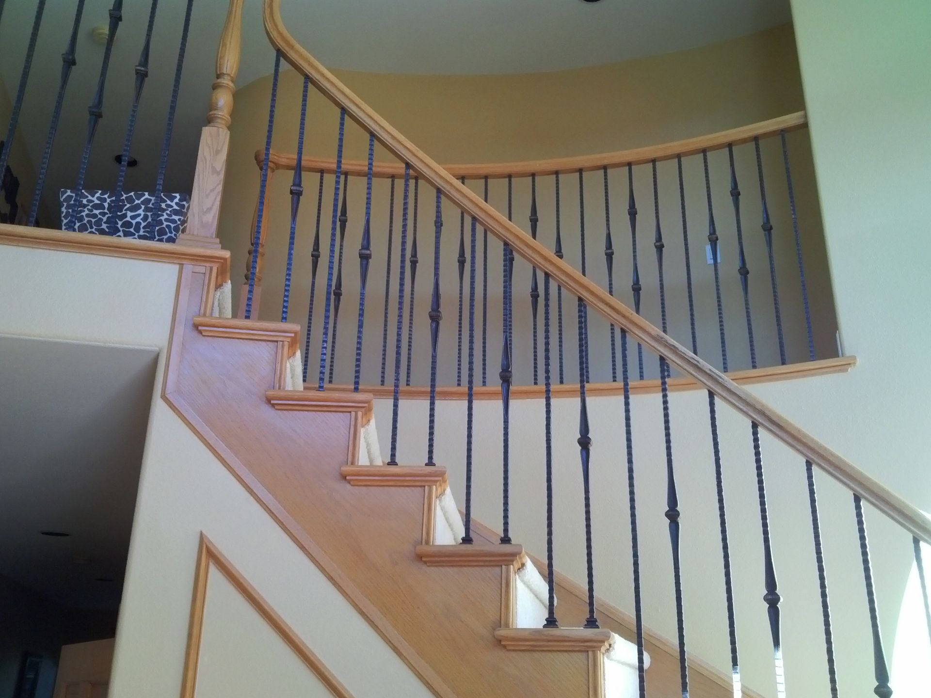 A wooden staircase with a wrought iron railing