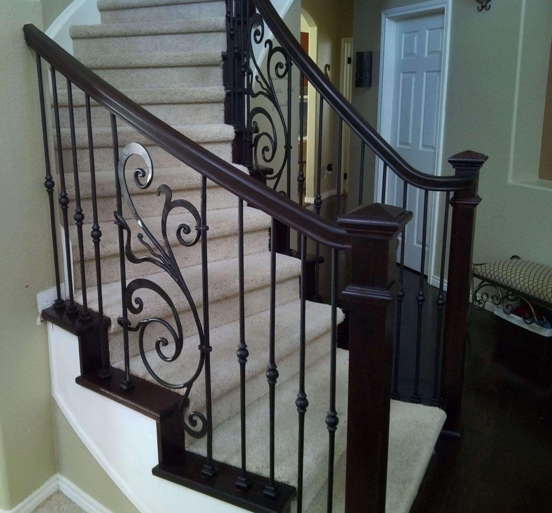 A staircase with a wrought iron railing and carpeted steps