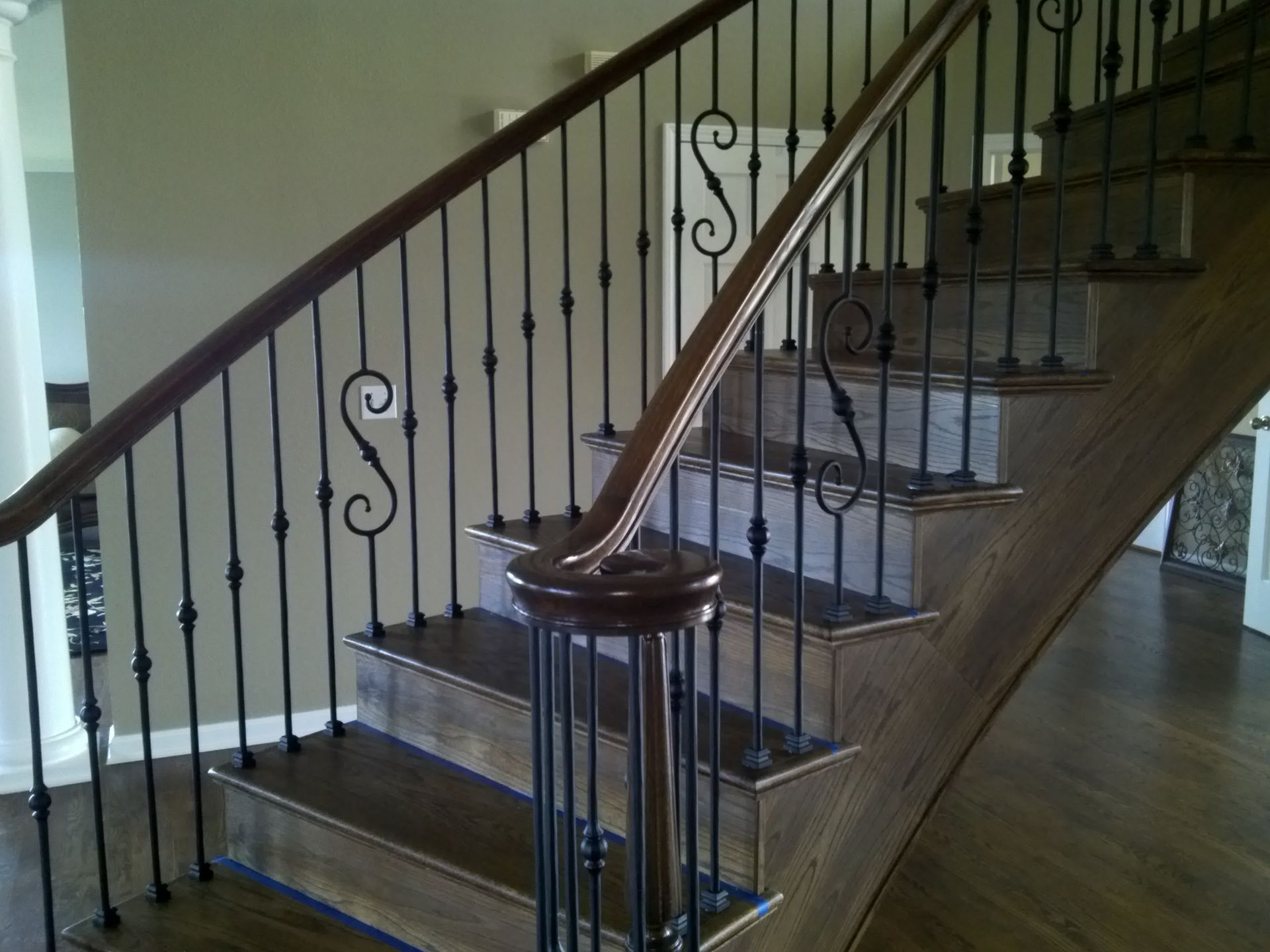 A wooden staircase with a wrought iron railing with the letter s on it