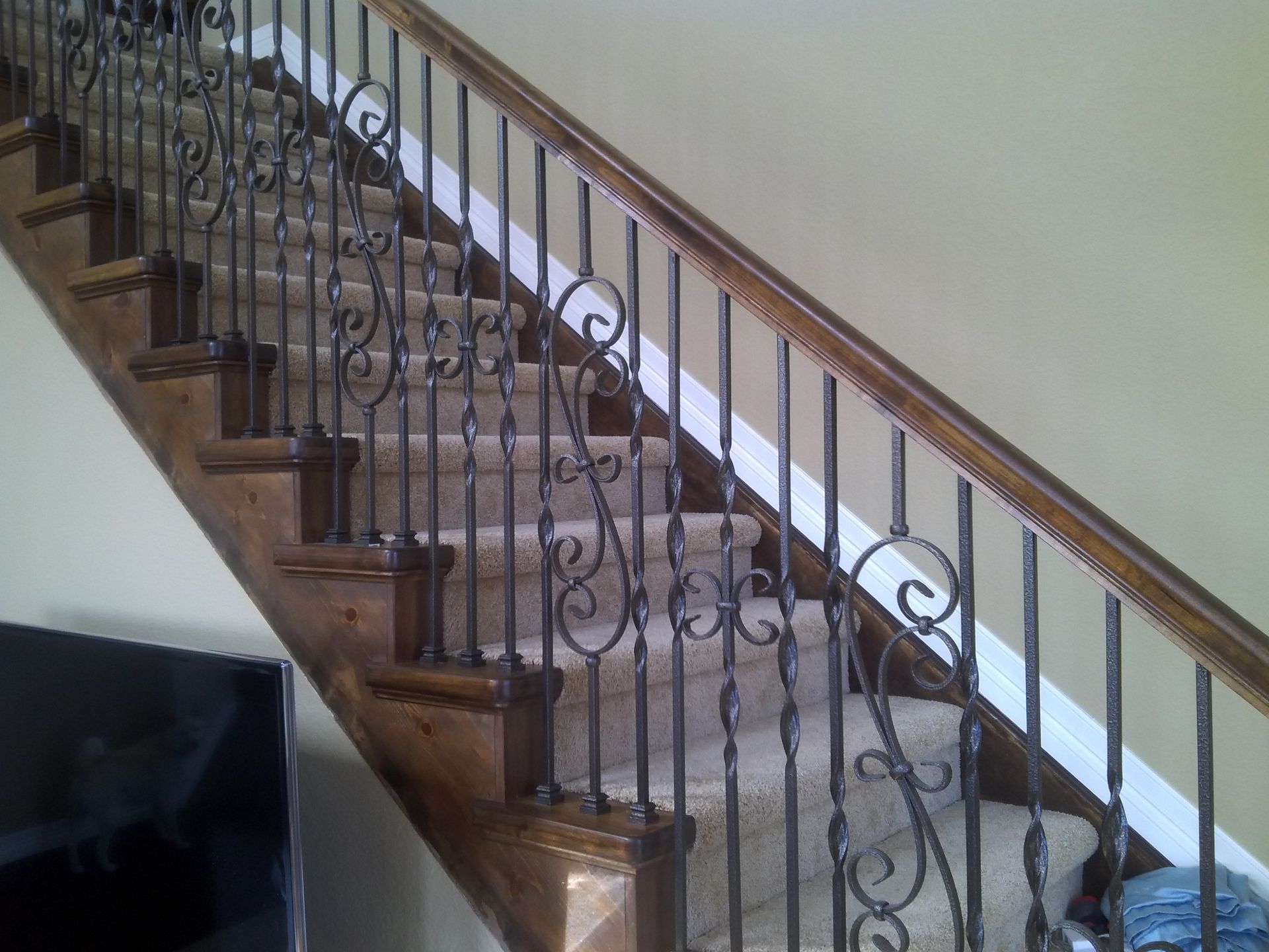 A wooden staircase with a wrought iron railing in a living room