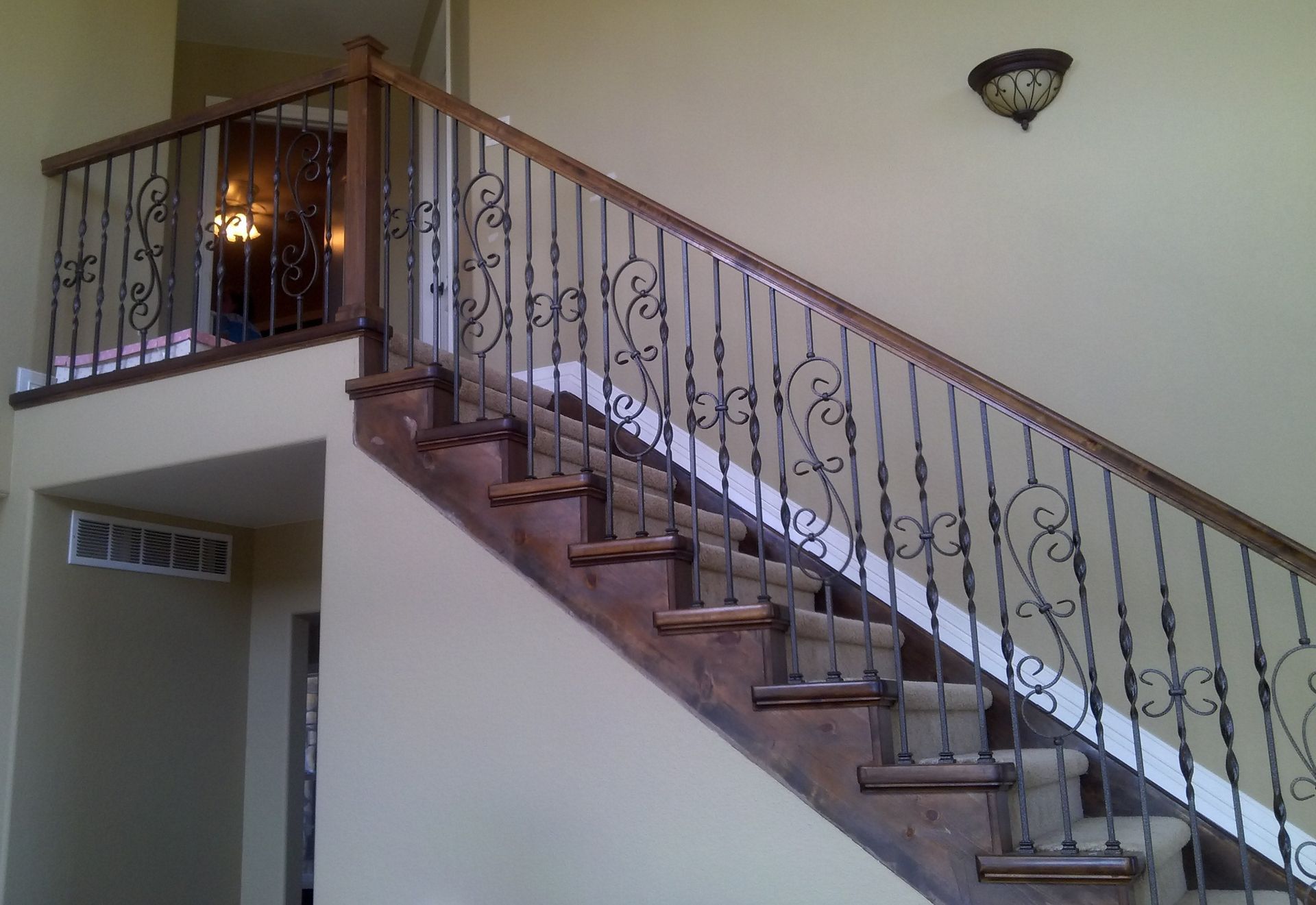 A staircase with a wrought iron railing and wooden steps
