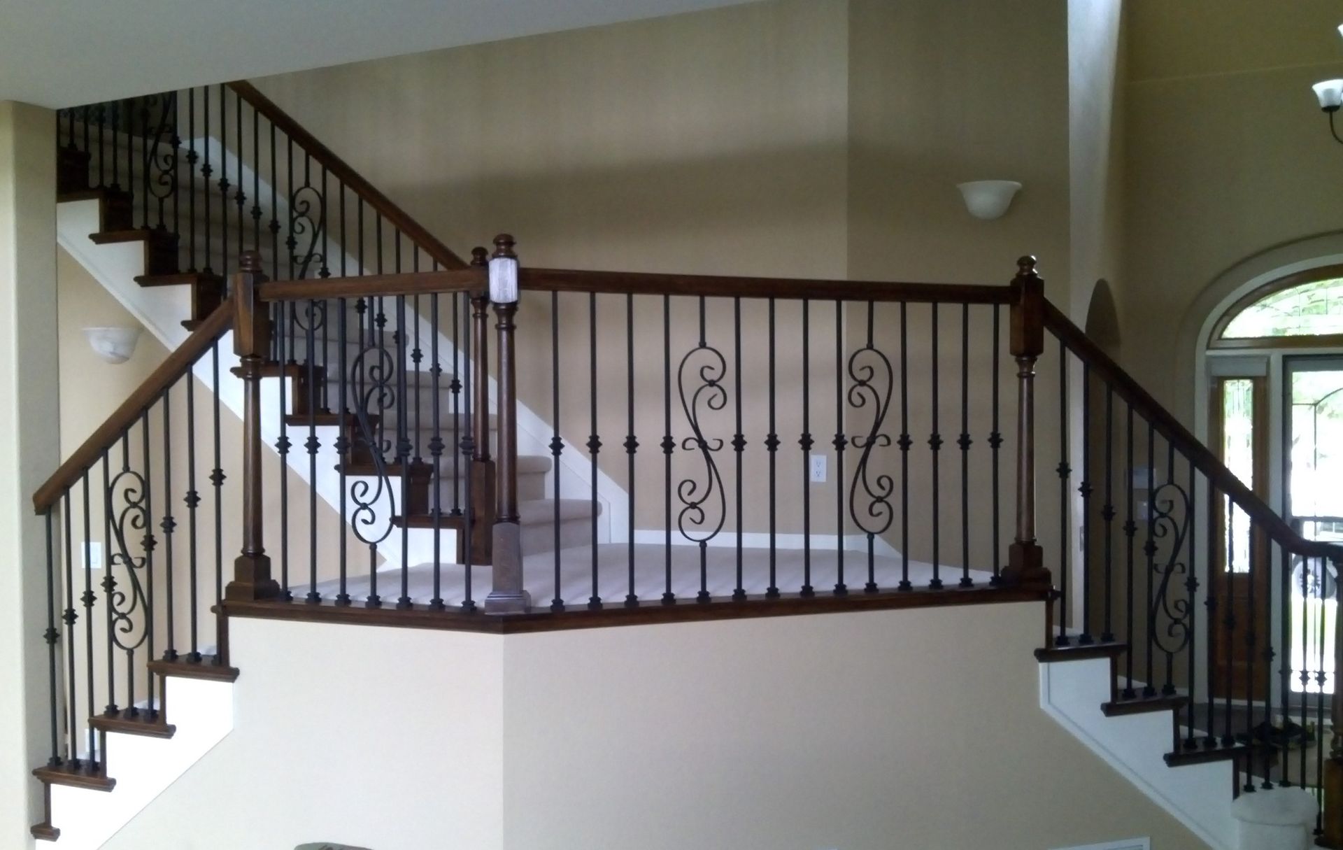 A staircase in a house with a wrought iron railing