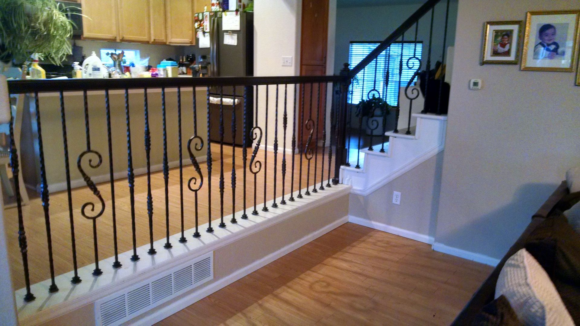 A living room with a staircase and a wrought iron railing