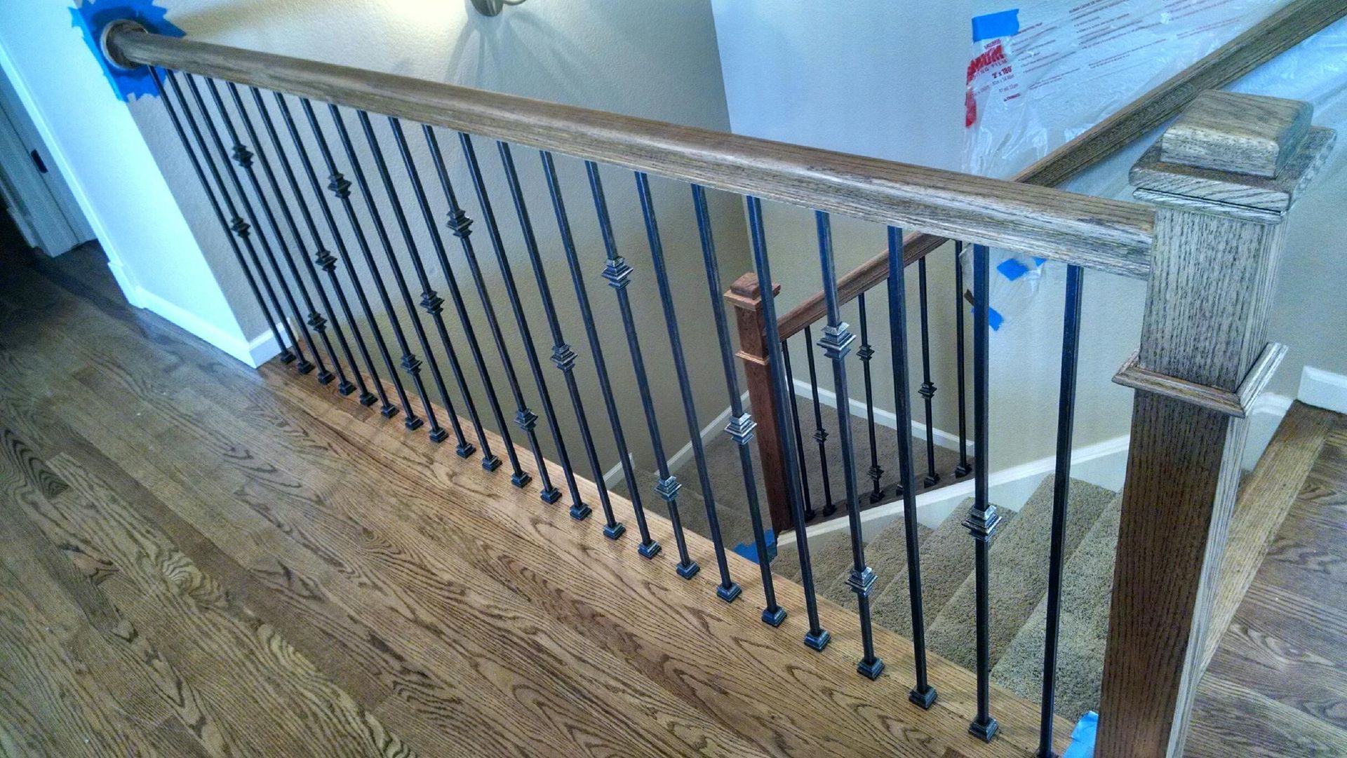 A wooden staircase with a wrought iron railing and a wooden handrail.