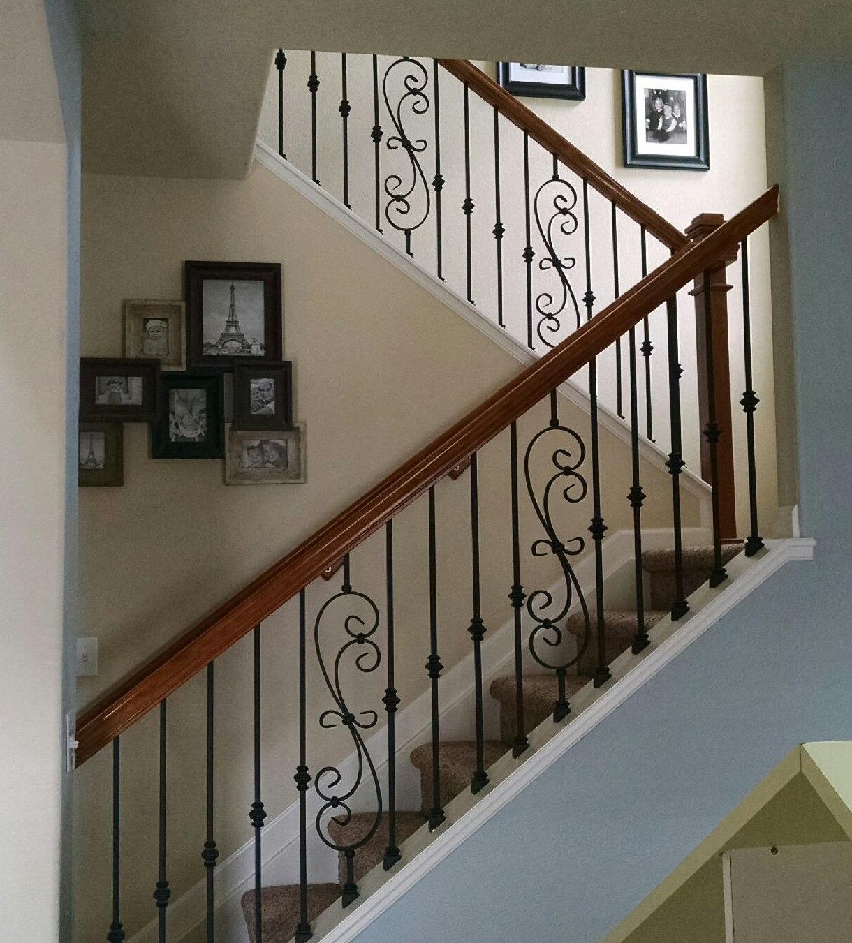 A staircase with a wrought iron railing and a wooden handrail
