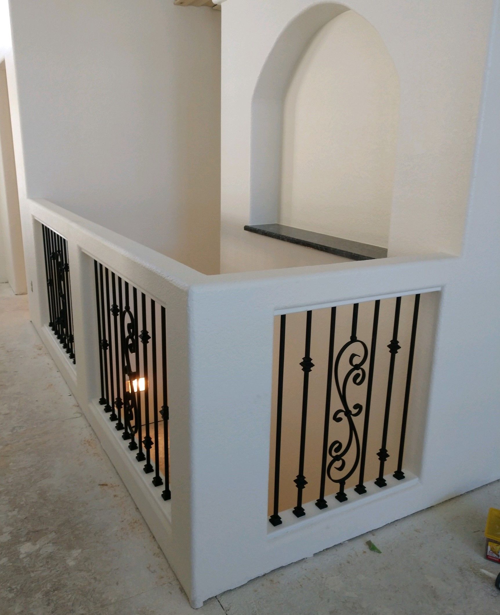 A white wall with a wrought iron railing on it